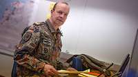 Ein Soldat sitzt an einem Schreibtisch, vor ihm ein Laptop.