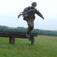 Zwei Soldaten rennen mit Gewehren G36 über die Hindernisbalken