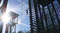 Fotografiert gegen das Licht: Ein Soldat überwindet den Seilsteg auf einem Kletterturm.