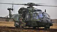 Ein Hubschrauber ist gerade gelandet. Soldaten springen nacheinander heraus.