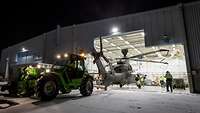 Aus einem Hangar wird ein Hubschrauber mit einem Rangierfahrzeug gezogen.