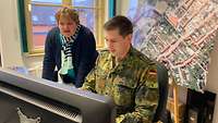 Eine Fra blickt gemeinsam mit einem Soldaten auf einen Bildschirm
