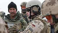 Ein deutscher Berater ist im Gespräch mit einem afghanischen Soldaten und gestikuliert dabei mit den Händen 