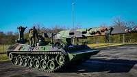 Zwei Soldaten stehen auf einem Panzer.