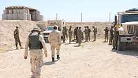 Einige afghanische Soldaten befinden sich innerhalb eines Sandwalls, sie halten sich dort zwischen zwei Fahrzeugen auf