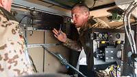 Ein Soldat unterweist einen anderen Soldaten in ein Störgerät
