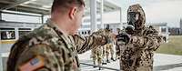 Die Soldaten müssen auch den Umgang mit dem Autoinjektor erlernen. Ein amerikanischer Soldat gibt einem deutschen Soldaten in ABC-Schutzkleidung ein Autoinjektor in die Hand