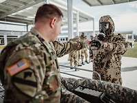 Die Soldaten müssen auch den Umgang mit dem Autoinjektor erlernen. Ein amerikanischer Soldat gibt einem deutschen Soldaten in ABC-Schutzkleidung ein Autoinjektor in die Hand