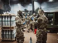 Soldaten in ABC-Schutzkleidung mit Prüfröhrchen in der Hand in einem Raum