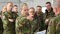 Im Kreis von Soldaten zeigt ein Soldat mit seinem Finger auf etwas.