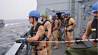 Soldaten stehen an Oberdeck und haben mit Leinen und einem Postbeutel eine Verbindung zu einem anderen Boot hergestellt