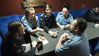Mehrere Soldatinnen und Soldaten sitzen an einem Tisch und unterhalten sich