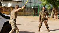 Ein Ausbilder simuliert eine Attacke mit einem Holzstab auf einen malischen Soldaten