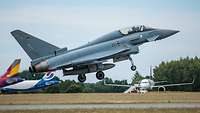 Ein Eurofighter ist kurz davor auf der Landebahn aufzusetzen, um direkt danach wieder durchzustarten.