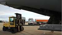 Ein Gabelstapler entlädt ein militärisches Transportflugzeug über die hintere Ladeluke