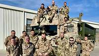 Mehrere Soldaten und eine Soldatin stehen um ein gepanzertes Fahrzeug 