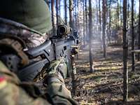 Ein Soldat schießt mit seiner Waffe in den Wald.