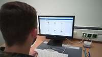 Ein Soldat sitzt vor einem Computerbildschirm