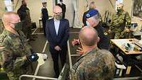 Mehrere Soldaten und ein Zivilist mit Alltagsmaske in einem Zelt im Gespräch