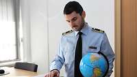 Ein Soldat steht am Schreibtisch und schaut in ein Buch