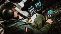 Ein Bordmechaniker sitzt im Cockpit eines Hubschraubers.