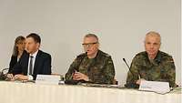 Mehrere ranghohe Militärs sitzen bei einer Pressekonferenz auf dem Podium gemeinsam mit dem sächsischen Ministerpräsidenten.