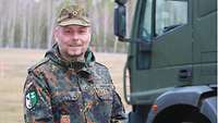 Ein Soldat vom Rang eines Oberstleutnant steht vor einem LkW. 