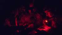 Zwei Soldaten schauen mithilfe einer Rotlichtlampe auf eine Karte