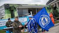 Fußball-Fan steht vor einem Karrieretruck der Bundeswehr und spricht mit einem Soldaten.