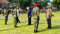 Ein Soldat und ein Mann im Anzug im Gespräch mit weiteren Soldaten