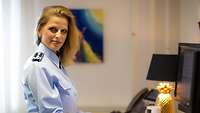 Portraitbild: Eine Frau steht vor ihrem Computer