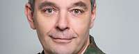 Ein General in Flecktarn-Uniform schaut freundlich in die Kamera.