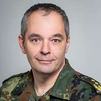 Ein General in Flecktarn-Uniform schaut freundlich in die Kamera.