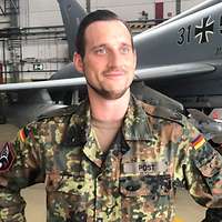Major Tobias Post steht vor einem Flugzeug in einer Halle und schildert seine Erlebnisse