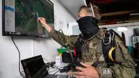 Ein Soldat zeigt mit einem Stift auf einen Bildschirm an der Wand