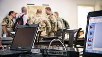 Laptop und Technik vor Soldaten im Hintergrund