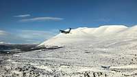 Ein A400M fliegt im Tiefflug durch die schneebedeckte Landschaft Norwegens. 