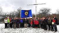 Abschlussfoto der Pilgergruppe aus Nordrhein-Westfalen mit einer blauen Fahne am Birkenkreuz
