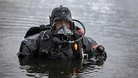 Ein Soldat mit kompletter Tauchausrüstung steht im Wasser, das ihm bis zur Brust reicht.