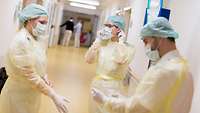 Medizinisches Personal zieht ihre Schutzkleidung auf dem Flur an.