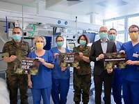 Aufruf Mehrere Personen halten kleine Plakate in der Hand und werben darum, dass alle Menschen zu Hause bleiben sollten.