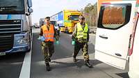 Soldaten verteilen auf einer Autobahn und Kaffee, rechts und links Lkws. Der Stau entstand wegen der Lage zu COVID-19.