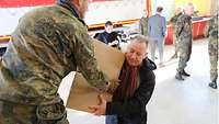 Zivil gekleideter Mann nimmt von einem Soldaten ein Paket entgegen.