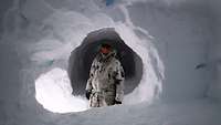 Ein Soldat in Schneetarn steht in einer weitläufigen Schneehöhle.