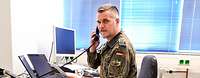 Ein Soldat sitzt an seinem Arbeitsplatz und telefoniert.