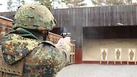 Ein Reservist zielt auf einer Schießbahn mit einer Pistole in beiden Händen auf eine Mannscheibe.