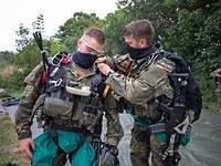 Ein Soldat hilft einem anderen Soldaten beim Anlegen seiner Ausrüstung