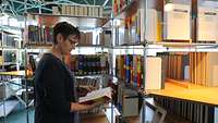 Employee of the Technical Information Center in Koblenz in front of book shelf