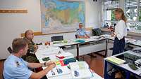 Eine Soldatin, zwei Soldaten und eine Lehrerin während eines Unterrichts im Kursraum am Bundessprachenamt.