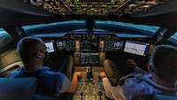 Beide Piloten sitzen im Cockpit, das voller Fluginstrumente steckt, und kontrollieren die Flug-Parameter.